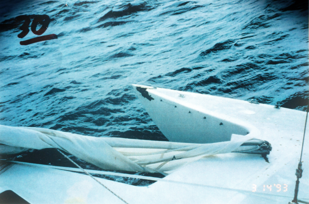Gold Eagle of Raleigh, showing damaged starboard ama after the trimaran survived a freak storm in the Gulf of Mexico. "I am not sure exactly when, but I suspect probably when the rogue wave hit, the sea anchor also tore loose a bridle leg, carrying with it the hardware for mounting the trampoline, because, sometime after daybreak we noted that the bridle for the right side of the sea anchor was totally gone. There was a hole in the bow on the right side [starboard ama], and the boat was riding to the sea anchor from one line, which was cleated off to the left side of the main bow." (Andrew Cserny photo).